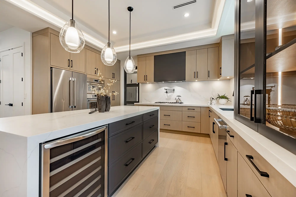 Modern kitchen with light wood cabinets, white countertops, and stainless steel appliances. Glass pendant lights and wooden floor.