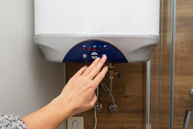 Hand adjusting a white water heater's temperature dial to 60°C. Wood panel background, visible pipes, and a cozy indoor setting.