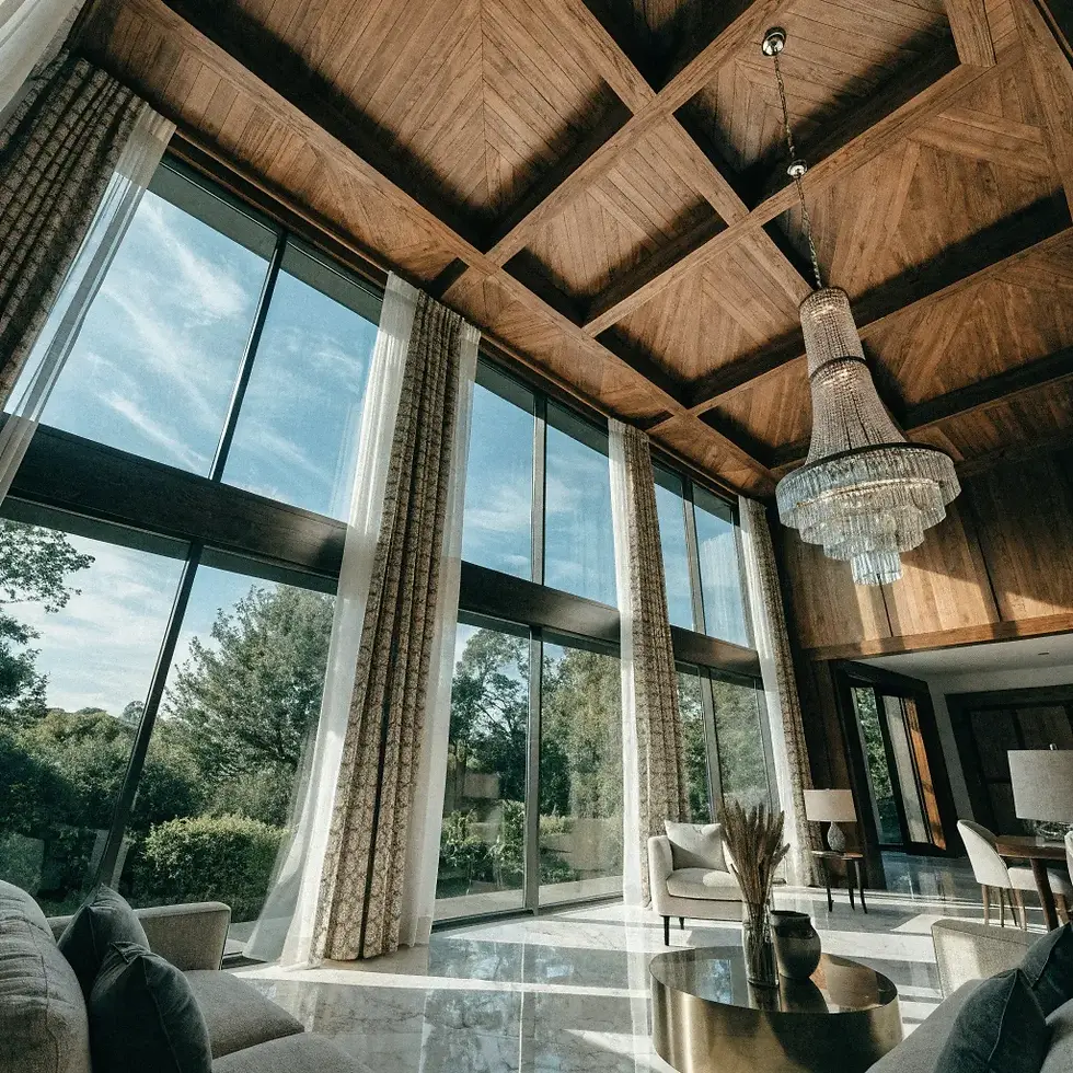 Luxurious living room with tall windows, a wooden ceiling, and a large chandelier. Soft sunlight filters in, creating a serene ambiance.