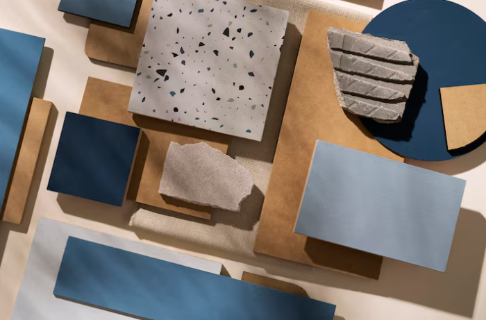 Various rectangular and circular tiles in blues and browns, some textured or speckled, arranged on a flat surface in sunlight.