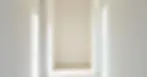 A hallway with white trim and off-white walls, demonstrating a subtle yet stylish contrast.