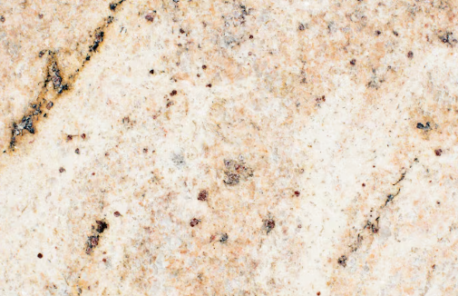 Speckled granite surface with a mix of beige, brown, and black patterns. The texture appears rough, with scattered dark spots.