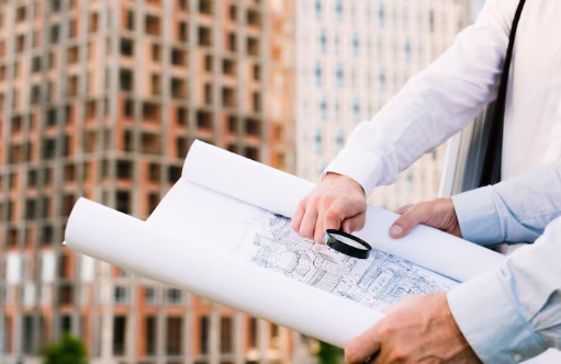 Architects review blueprints with a magnifying glass against a cityscape of modern, tall buildings. Bright and focused atmosphere.