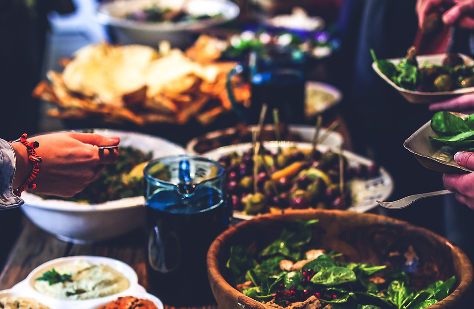 Hands serving fresh plant-based food at a vibrant café with callout text encouraging online orders at Folia on Galiano