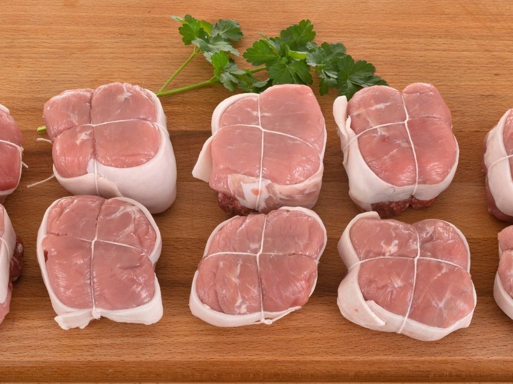 Paupiettes de veau crues prêtes à cuire sur une planche en bois.