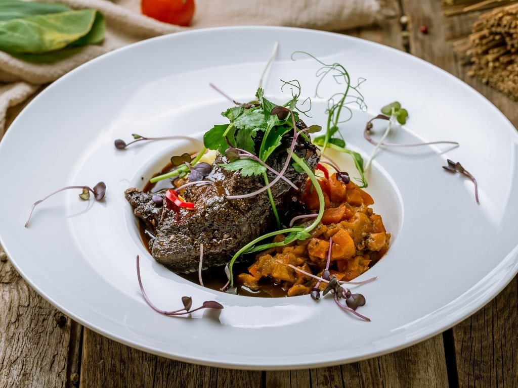 Joue de bœuf mijotée avec garniture et dressage gastronomique.