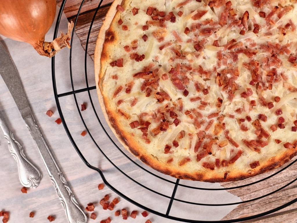 Flammekueche fine garnie de crème, oignons et lardons.