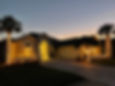 Palm trees and house adorned with holiday lighting at dusk.