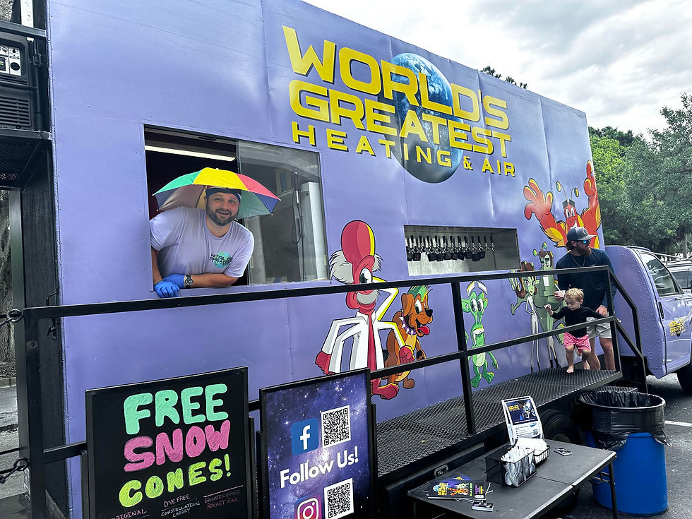 World's Greatest Heating & Air's signature purple HVAC event truck featuring colorful alien mascots and free snow cones at a Northeast Florida community event, showcasing the company's commitment to family fun and community involvement.