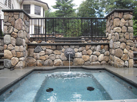 natural stone pool surround with custom masonry wall and water feature in Brookline Massachusetts