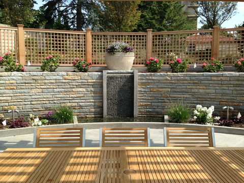 natural stone retaining wall with central water feature, custom granite planter boxes, patio seating, and landscape installation in Massachusetts