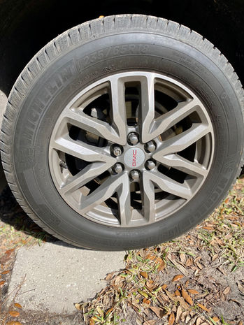 Before image of the tire and wheel on a Dark Blue GMC Acadia, showing significant brake dust accumulation on the wheel surface.