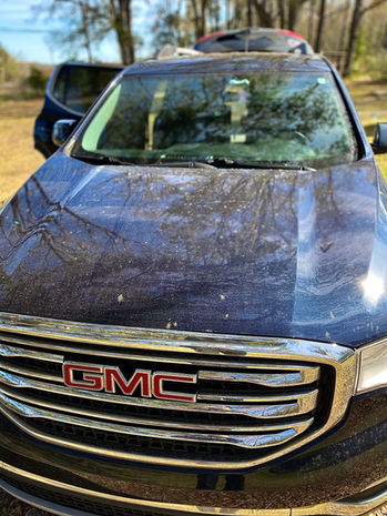 Before image of a Dark Blue GMC Acadia showing a heavily soiled front view with dirt, pollen, and road grime covering the surface.