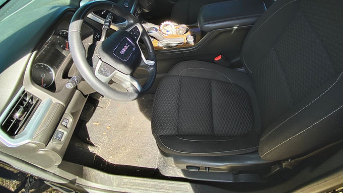 Before image of the front driver seat in a Dark Blue GMC Acadia, showing noticeable stains, dirt, and debris on the seat fabric.