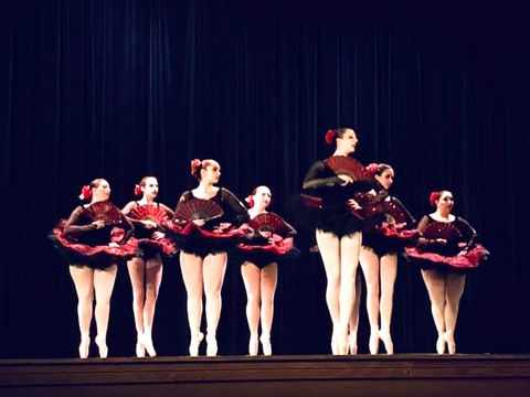 Ballet dancers in black and red costumes on stage en pointe