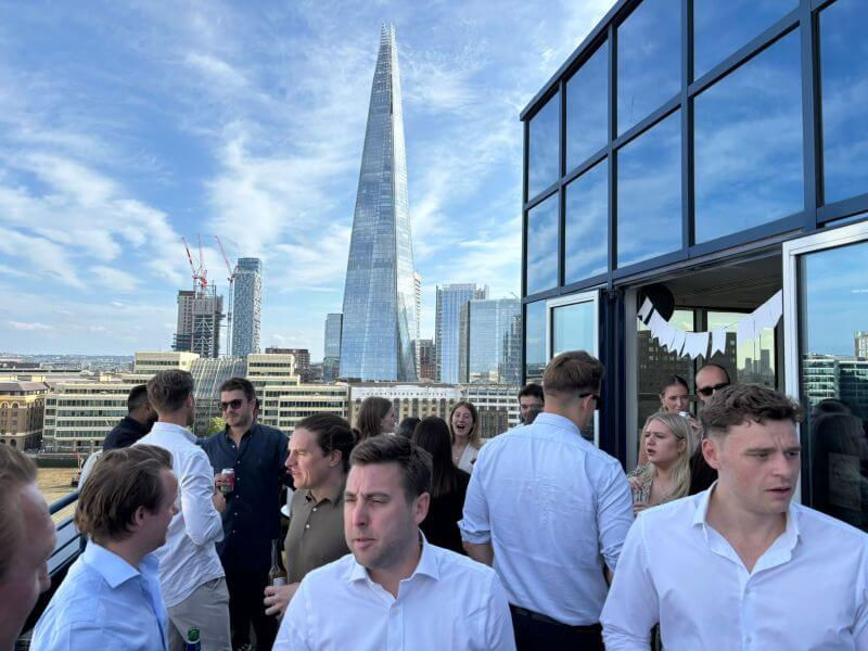 Max Woolger among guests on Beaumont Bailey’s rooftop terrace in London, with The Shard in the background during their six-year celebration.