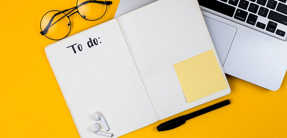 Open to-do list notebook with glasses, laptop, pen, earbuds, and sticky note on a yellow background.