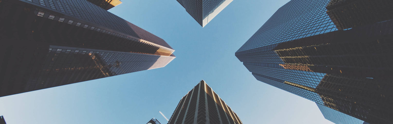 4 modern glass office towers captured from below, representing corporate innovation and professional services.