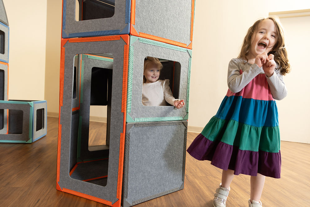 Two girls playing in a superspace block fort, laughing