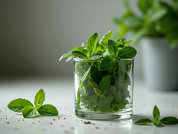 Organic peppermint leaves in a clear glass being prepared for herbal infusions.png