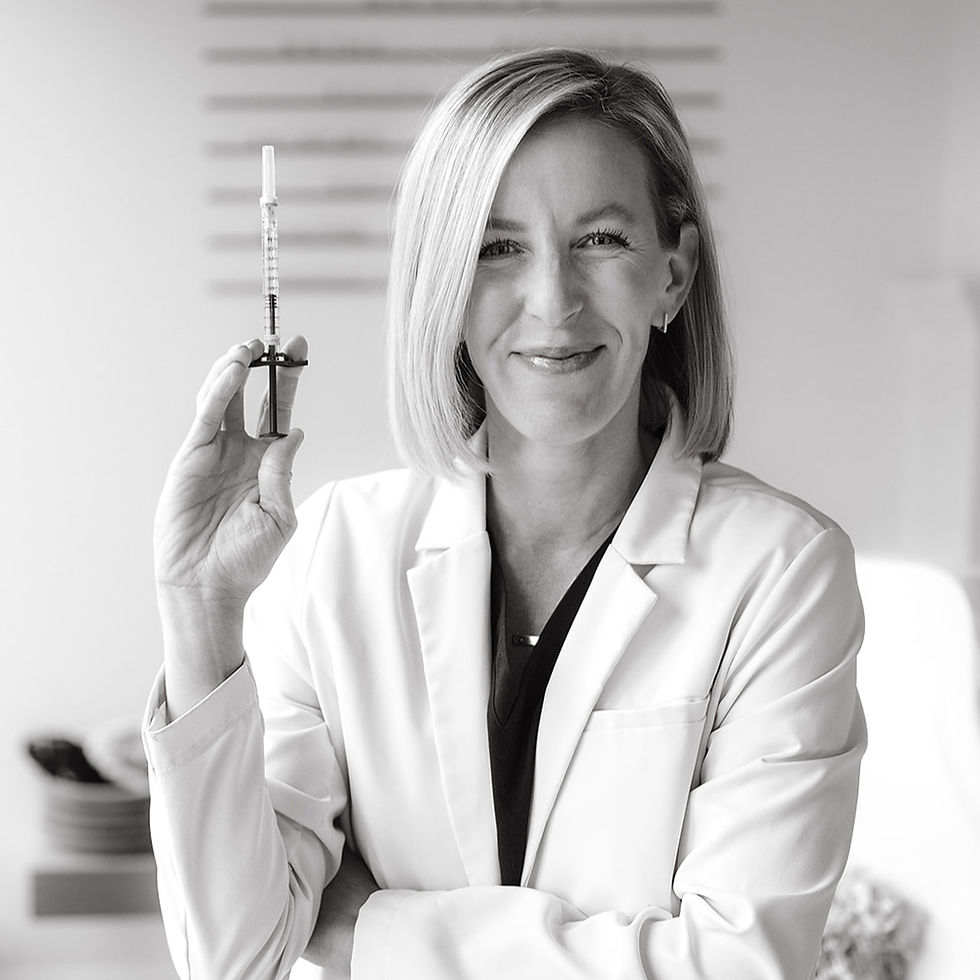 Smiling woman in a white lab coat and black scrubs stands indoors, light hair, neutral background, wearing a "FIGS" nametag, professional mood.