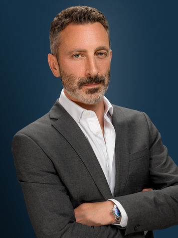 Professional business portrait of a man in a grey suit against a blue background
