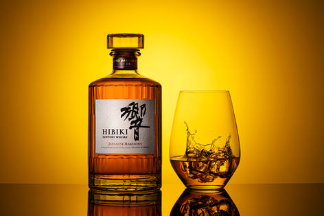 Hibiki Japanese whisky bottle and glass against an amber background