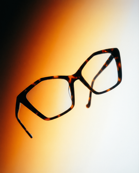 Tortoiseshell eyeglasses suspended against an amber-to-white gradient background.