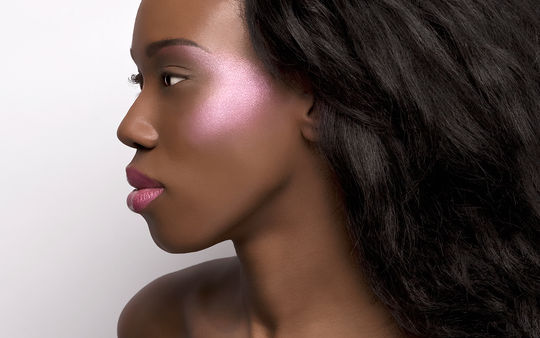 Black woman in profile with metallic purple cheek highlight