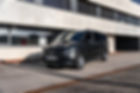 Schwarzer Mercedes-Benz V-Klasse Van von vorne links vor einem modernen Gebäude.