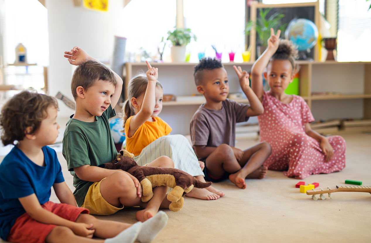 group-small-nursery-school-children-sitting-floor-indoors-classroom-raising-hands (1).jpg