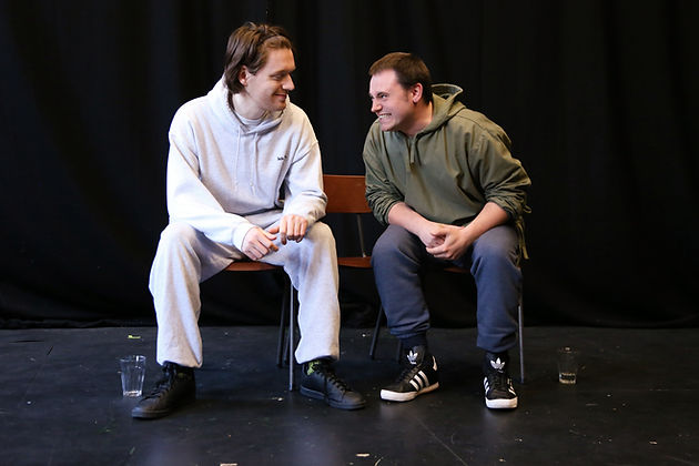 Two actors smiling at eachother