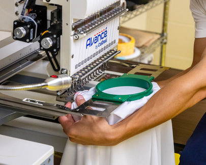 Brothers Threads student operating an Avance embroidery machine, embroidering a performance polo with a custom company design.