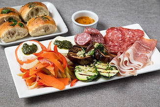 antipasti dish with grilled vegetables, prosciutto, salami, and caprese salad