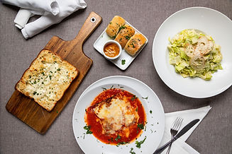 garlic bread with cheese, lasagna, and a Caesar salad