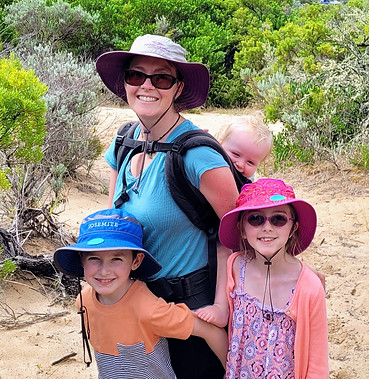 mum weaing toddler on her back with two children stanging with her, out for a hike