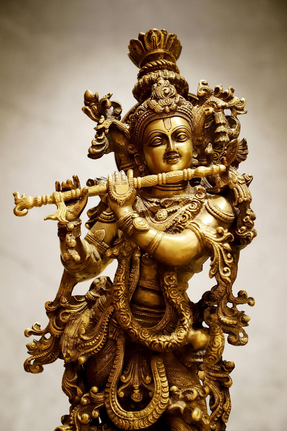Golden brass statue of Lord Krishna playing the flute, representing Indian mythology and legends.