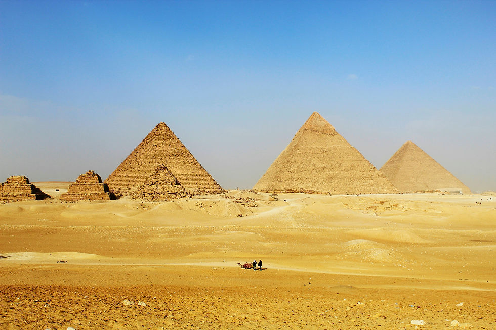 Majestic ancient pyramids emerge from the expansive, dry desert beneath a clear blue sky, showcasing timeless architectural brilliance.
