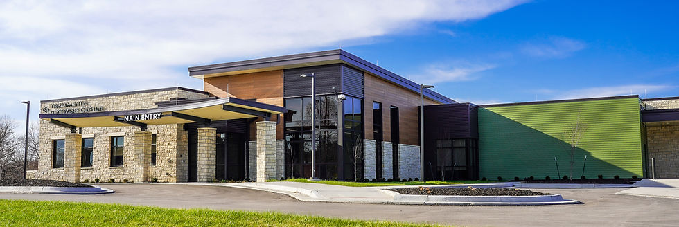 The Treatment & Recover Center. A limestone facace connects to a wooden and glass building.