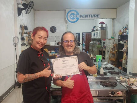 Chef Apple presenting a graduation certificate to a happy student at our DTV cooking class in Chiang Mai.