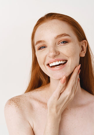 close-up-of-young-beautiful-redhead-woman-smiling-at-at-front-touching-perfect-clean-skin-