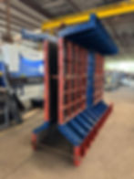 Forma metálica reforçada em azul e vermelho para concretagem de elemento estrutural especial, em ambiente fabril.