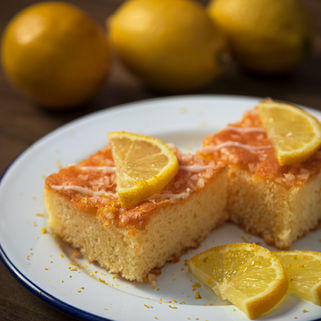Slices of lemon cake topped with fresh lemon on a plate.