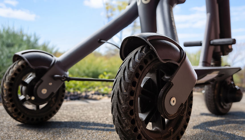 Low-angle close-up of the front wheels and suspension of the Supersmith 3Scooter outdoors.