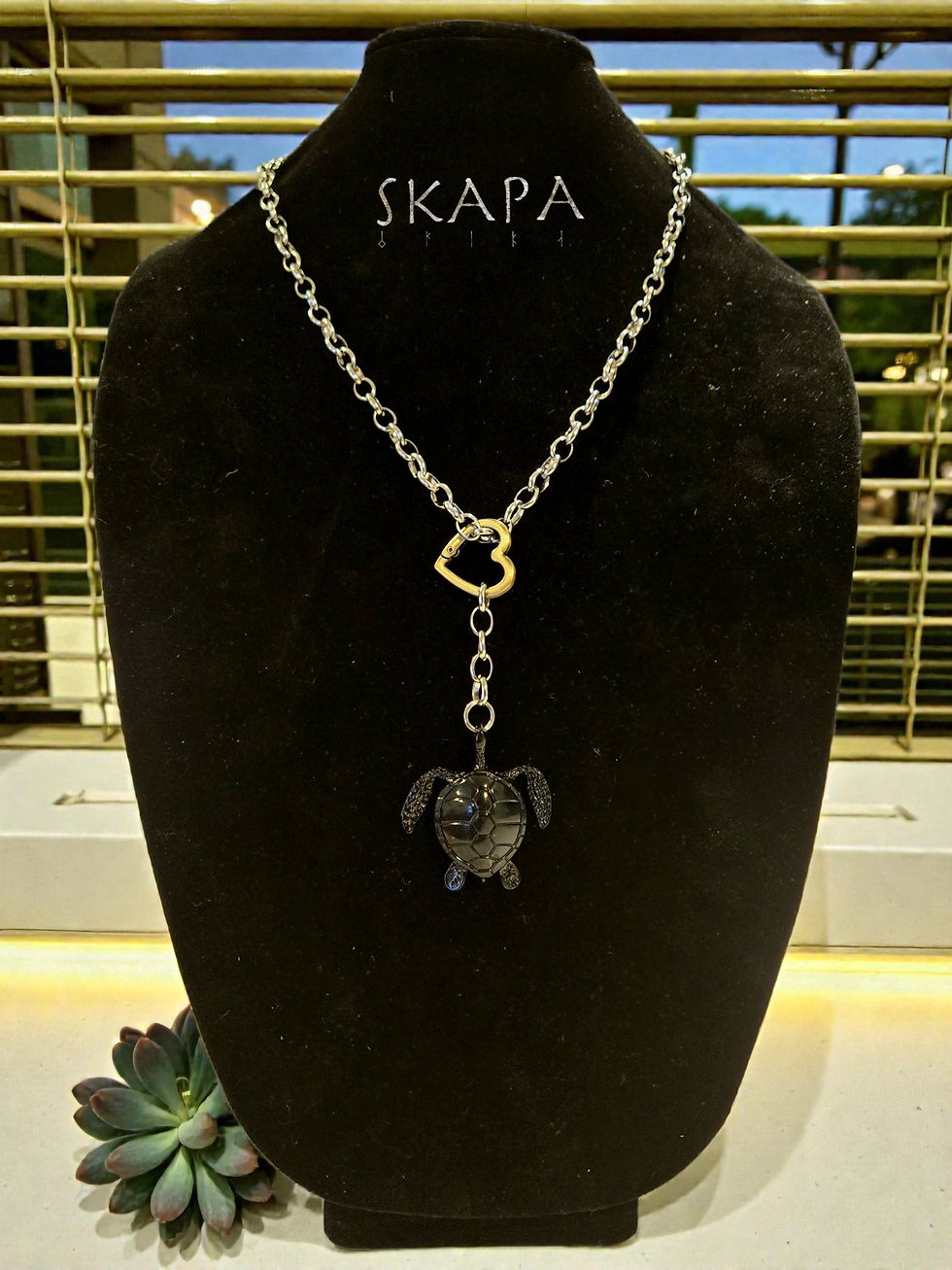 A sleek black metallic sea turtle lariat necklace featuring a tiny turtle charm captured in a clear resin window.