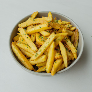 a bowl of fries sprinkled with chopped herbs 