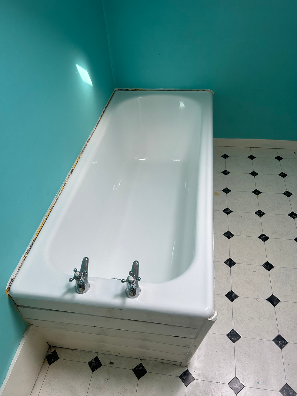 White bathtub with chrome hot and cold tap handles set against turquoise walls and black-and-white patterned vinyl flooring