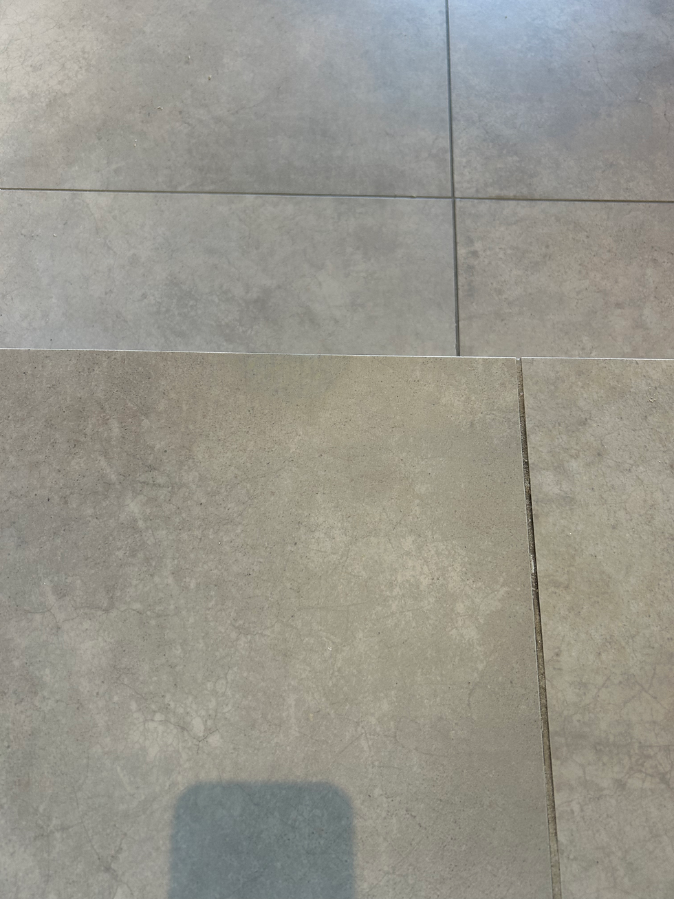 Grey stone-effect floor tiles with thin grout lines showing a step transition