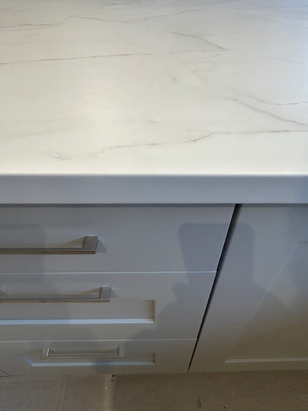 White marble-look countertop over white kitchen cabinets with brushed metal horizontal handles