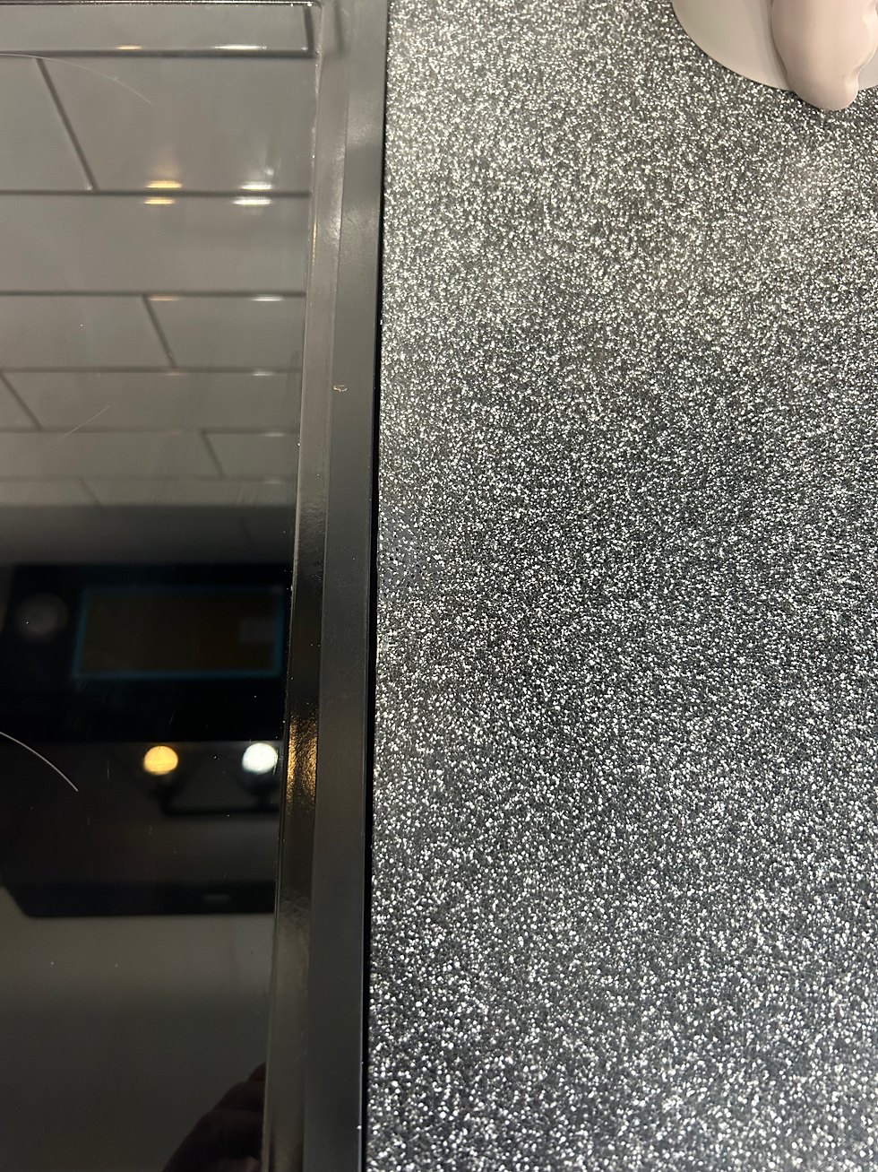 Grey kitchen worktop with visible crack repaired using masking tape, set in a modern kitchen space.